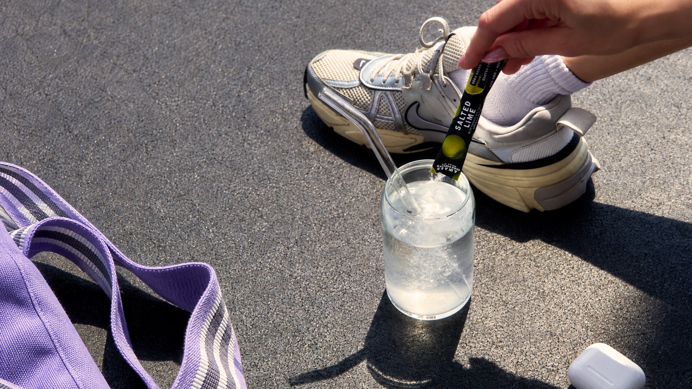 A Salted Lime electrolyte stick poured into a glass beside a sneaker